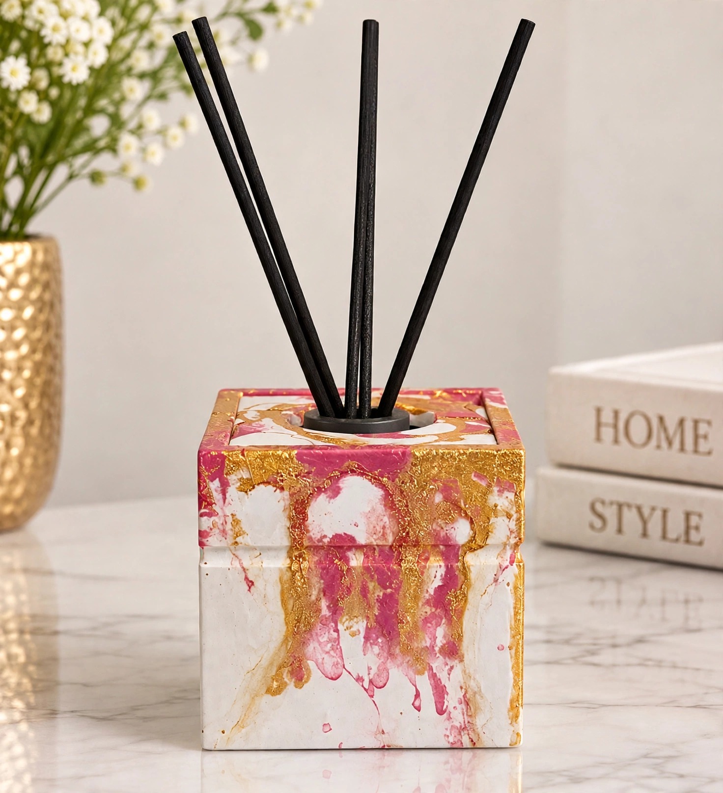 Reed diffuser in a pink, white and gold marbled square vessel, with black reeds and a plain black insert
